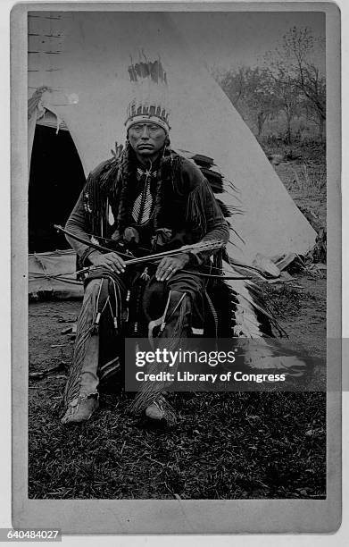 Parker; Quanah, Comanche chief that resisted the settlement of White ranchers on the Texas prairie sits with bow and arrow in hand in front of his...