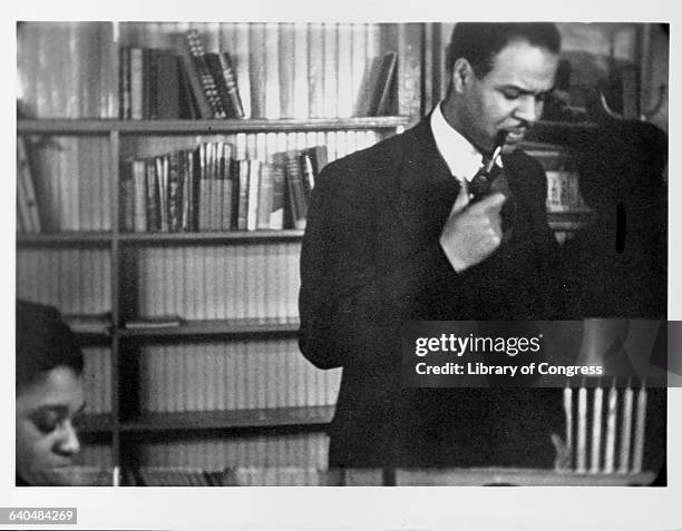 Roy Wilkins stands smoking a pipe. Wilkins was a civil rights leader and the director of the National Association for the Advancement of Colored...