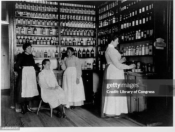Nurses treat a young North American Indian student in an infirmary line with medicine bottles, Carlisle Indian School, Carlisle, Pennsylvania. |...