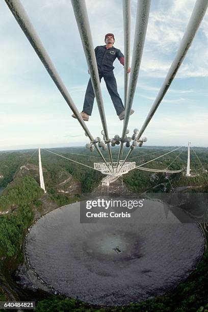 Technician Luis Heredia checks some the cables which suspend the receiver over the radio telescope dish at the Arecibo Radio Telescope. | View from:...