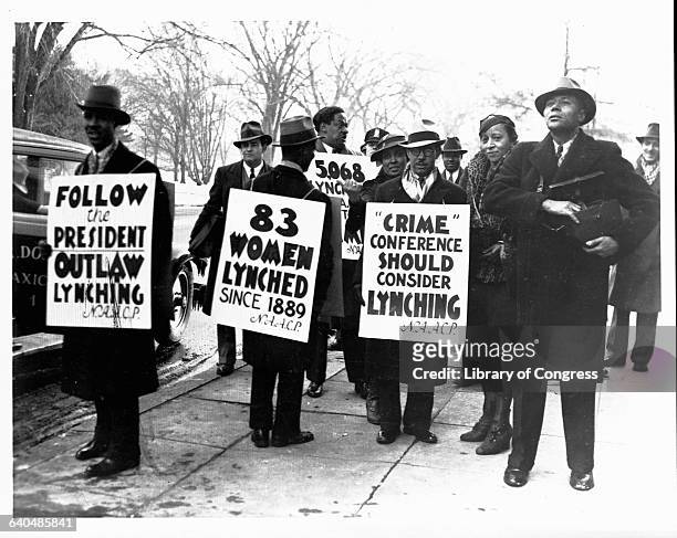 Members of the National Association for the Advancement of Colored People hold signs protesting the practice of lynching while a conference on crime...