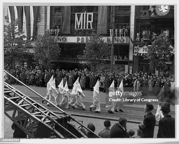 Men dressed in Ku Klux Klan robes march down the street in a Communist political parade sponsered by the Gottwald regime in Czechoslovakia to...