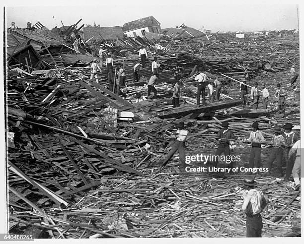 Men use ropes to pull away the debris of houses in order to look for bodies, after the Galveston Hurricane of 1900.