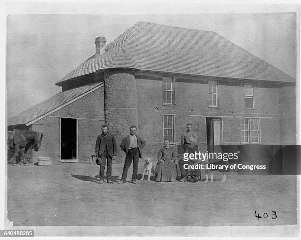 Family gathers in front of a sod house.