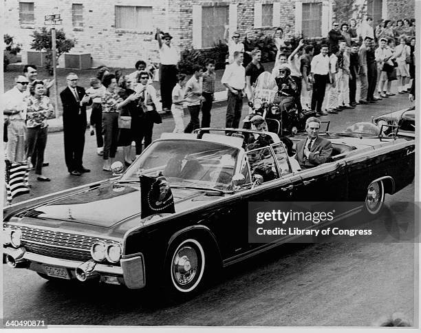 John Fitzgerald Kennedy waves to the crowd from an open air limousine carrying Governor Connally of Texas and Jacqueline Kennedy, November 21, 1963.