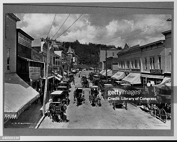 Horse-drawn carriages file past Main Street storefronts on Mackinac Island in Michigan.