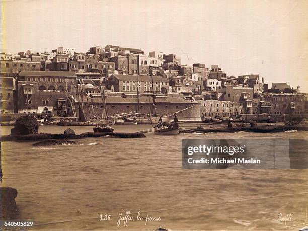 Small boats are shielded behind a breakwater at the port of Jaffa, Palestine, part of the Ottoman Empire.