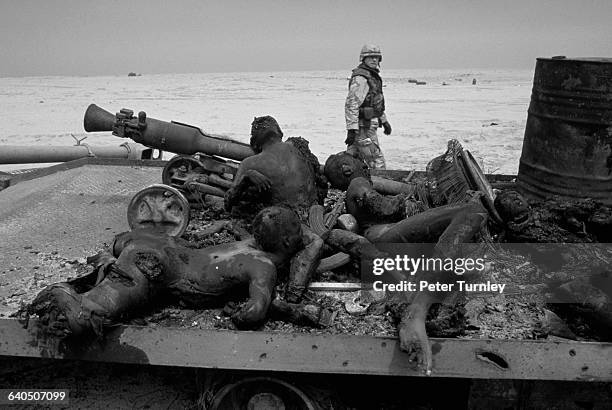 Few days after the end of the Gulf ground war, an American soldier inspects the carbonized bodies of Iraqi soldiers on the flat bed of a truck who...