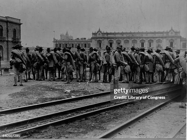 United State Marines arrive at the port of Veracruz to intervene in the Mexican Revolution. They stand on railroad tracks in the central plaza....