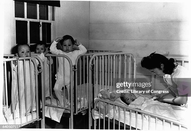 Nursery worker cares for orphaned infants at the Manzanar Relocation Center, California, ca. 1943. | Location: Manzanar Relocation Center, Lone Pine,...