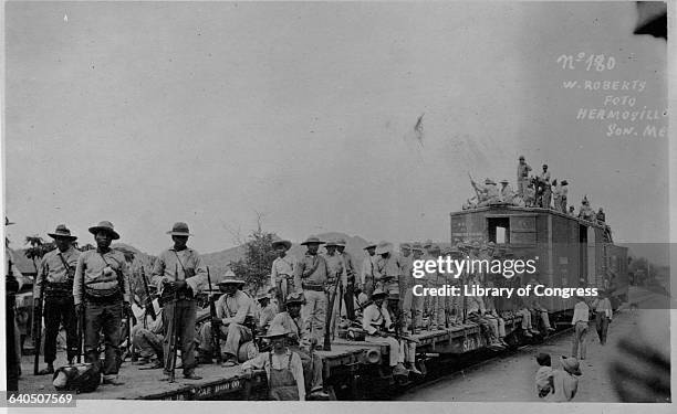 Group of Mexican soldiers ride a flatbed freight car to the next battle in the Mexican Revolution. Hermosillo, Sonora, Mexico.