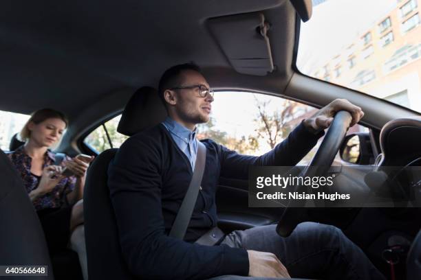 man driving with woman sitting in car - management car smartphone stock pictures, royalty-free photos & images