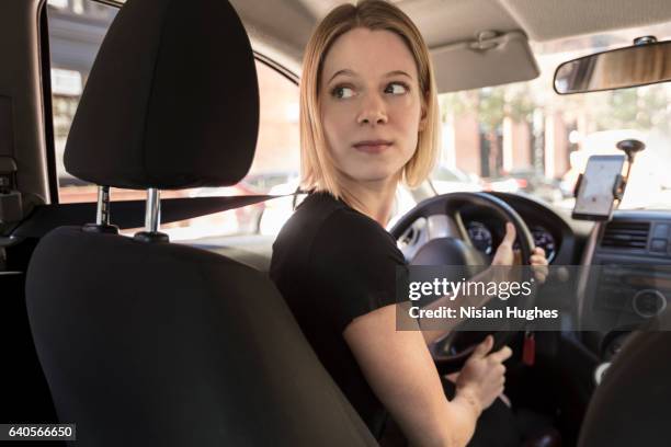 woman driving car - woman looking over shoulder serious stock pictures, royalty-free photos & images