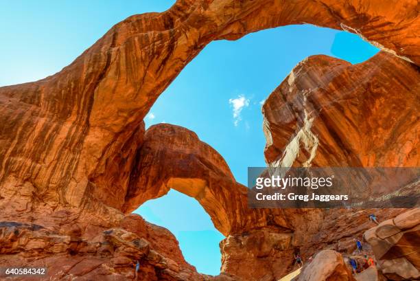 tourists explore double arch, arches national park, moab utah - arches national park fotografías e imágenes de stock