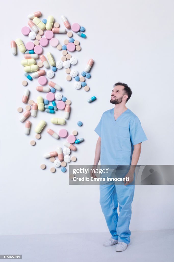 Happy young doctor watching medicine fall down
