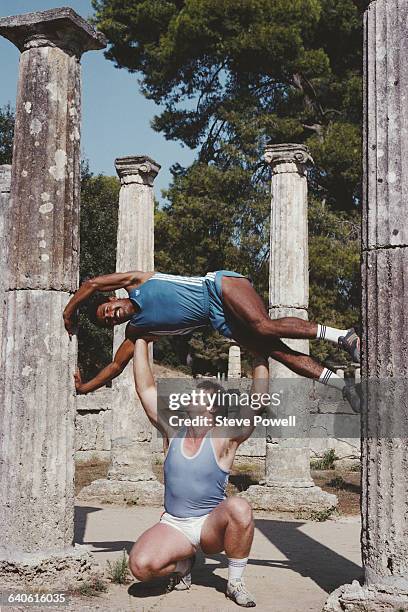 British discus thrower Richard Slaney holds aloft decathlete Daley Thompson on 1 March 1984 at the ancient Greek Temple of Hera in Olympia, Greece.