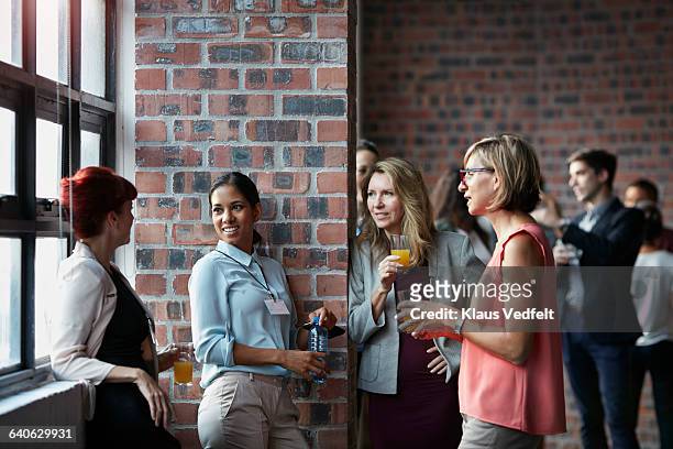 businesspeople socializing by window of auditorium - standing water stockfoto's en -beelden