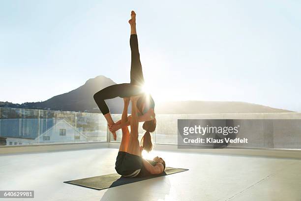 couple doing acrobatic yoga on rooftop terrace - rooftop stock-fotos und bilder