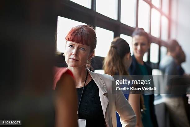 businesspeople socializing by window of auditorium - older woman colored hair stock pictures, royalty-free photos & images