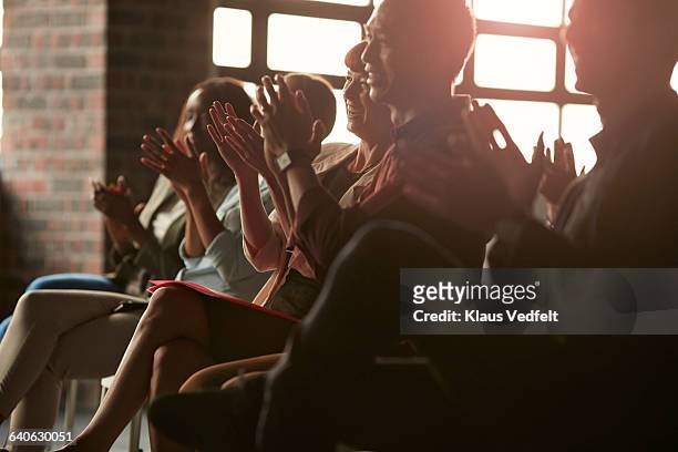 group of businesspeople clapping at lecture - aclamar fotografías e imágenes de stock