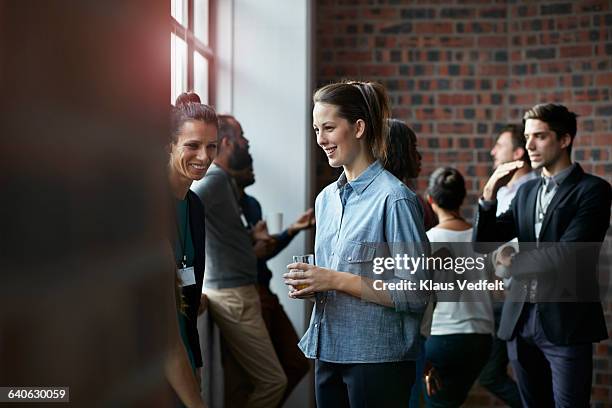 businesspeople socializing by window of auditorium - community college stockfoto's en -beelden