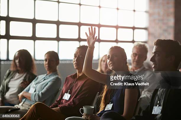 businesswoman with raised hand at convention - braccia alzate foto e immagini stock
