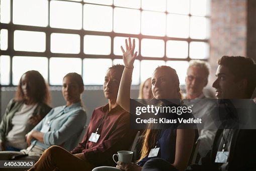 Businesswoman with raised hand at convention Businesswoman with raised hand at convention