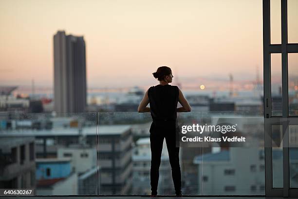 woman enjoying view from penthouse apartment - penthouse stock-fotos und bilder