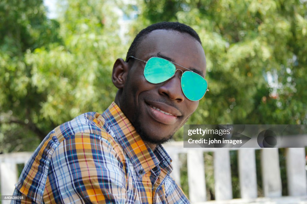 A young person smiling with his glasses