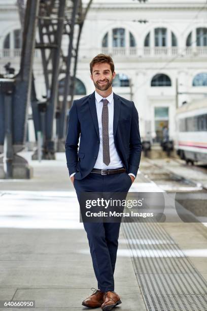 sonriendo el ejecutivo con las manos en los bolsillos en la estación de - man suit fotografías e imágenes de stock