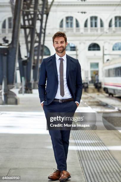 smiling executive with hands in pockets at station - business man front foto e immagini stock
