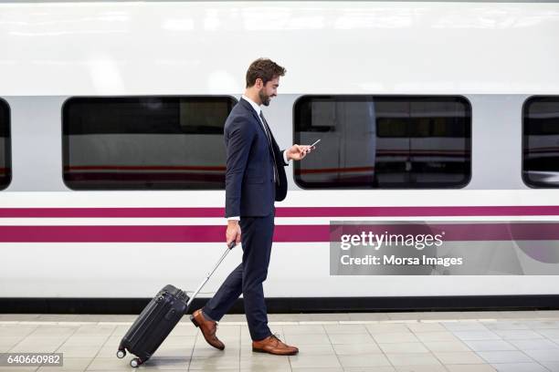 vista lateral del empresario con el teléfono en la estación de - train platform fotografías e imágenes de stock