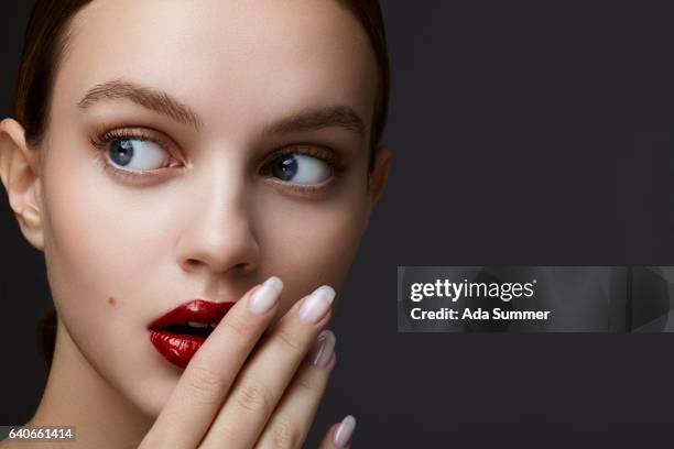 woman with red glossy lips covering her mouth with her hand - lippen stock pictures, royalty-free photos & images