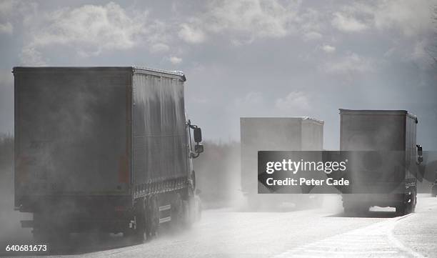 grey lorries driving on wet road - traffic pollution stock pictures, royalty-free photos & images