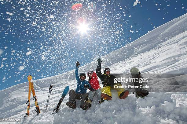 friends throwing snow sat on ski slope - winter friends playing stock-fotos und bilder