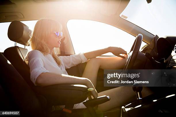 a female sitting in the drivers seat of a car. - hot legs stock pictures, royalty-free photos & images