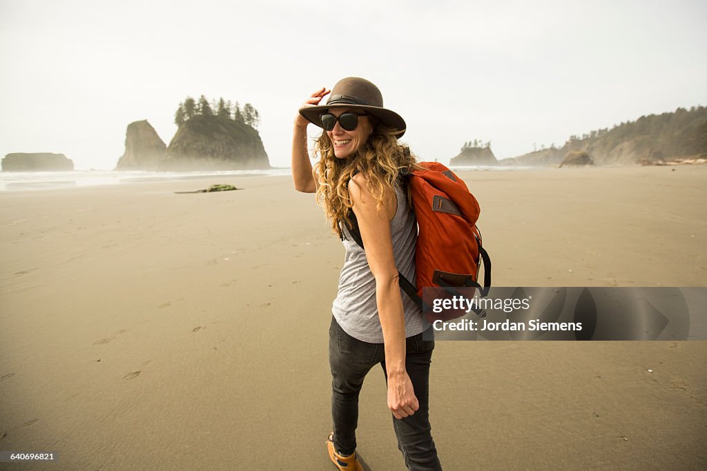 A woman hiking along a remote beach.