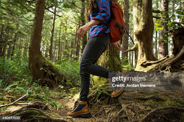 a woman hiking in a dense forest. - hiking boot stock pictures, royalty-free photos & images
