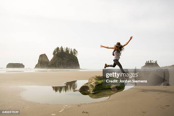 a woman hiking along a remote beach. - puddle fotografías e imágenes de stock