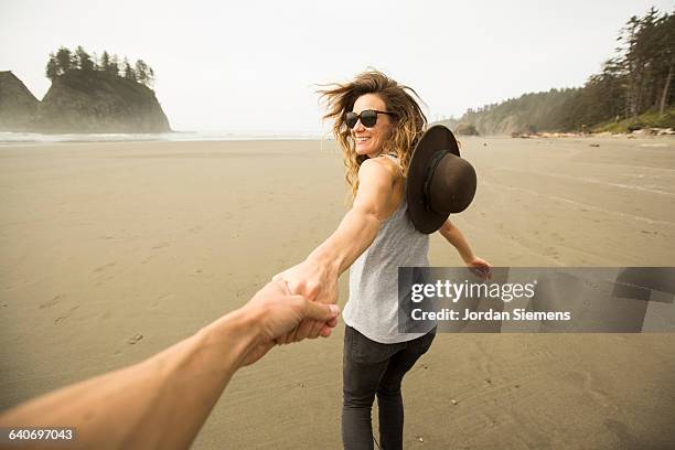 a woman hiking along a remote beach. - couple holding hands fotografías e imágenes de stock