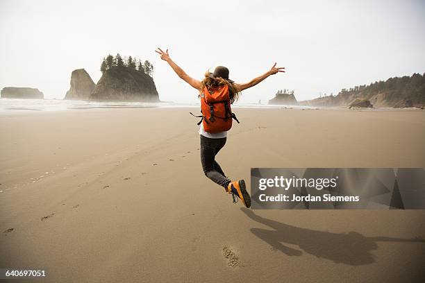 a woman hiking along a remote beach. - arms raised stockfoto's en -beelden