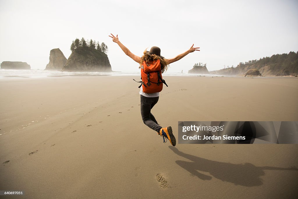A woman hiking along a remote beach.