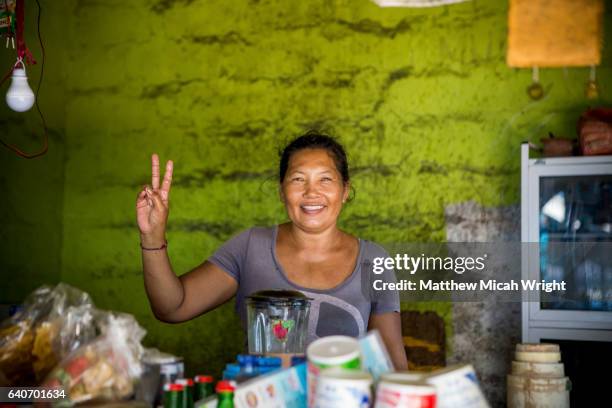 a local woman shows off her restaurant or "warung" on serangan beach, bali. - indonesia imagens e fotografias de stock