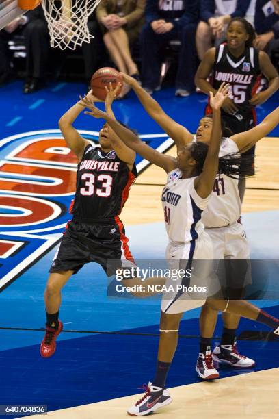 Monique Reid of the University of Louisville drives past Tina Charles and Kaili McLaren of the University of Connecticut during the Division I...