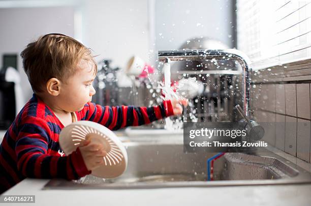 1 year old boy playing with water - haushaltsarmatur stock-fotos und bilder