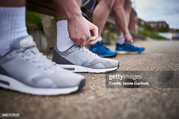 two males tying their shoes preparing for a run - change socks stockfoto's en -beelden