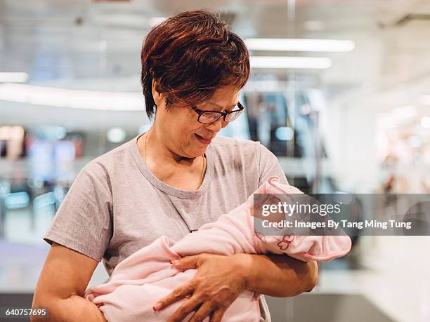 grandma holding a sleeping baby in mall - red and pink outfit stock pictures, royalty-free photos & images