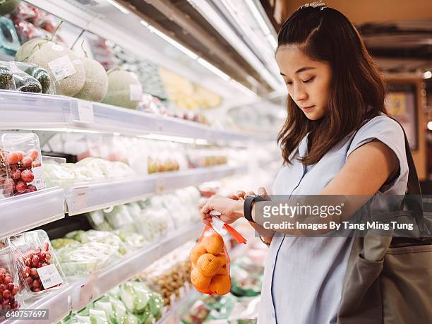 pregnant mom using smart watch in supermarket - multiple smart devices stock-fotos und bilder