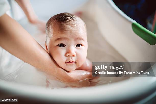 new born baby having tub bath joyfully - bad haircut stockfoto's en -beelden