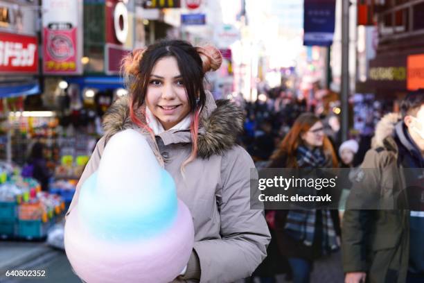 young woman eating cotton candy - slavische-volkeren stockfoto's en -beelden